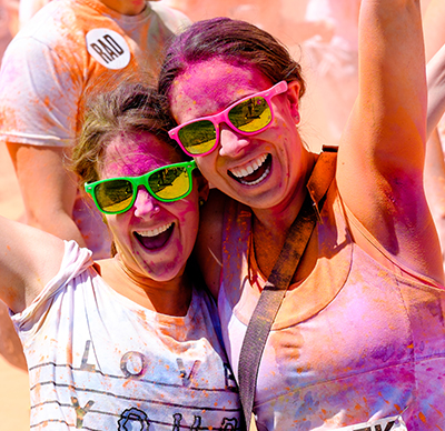 Toronto, Ontario, Canada - May 31, 2014: Two Female runners splattered with colourful powder smiling and cheering at the the Color Me Rad 5K Color Run on May 31, 2014 in Toronto, Ontario Canada.